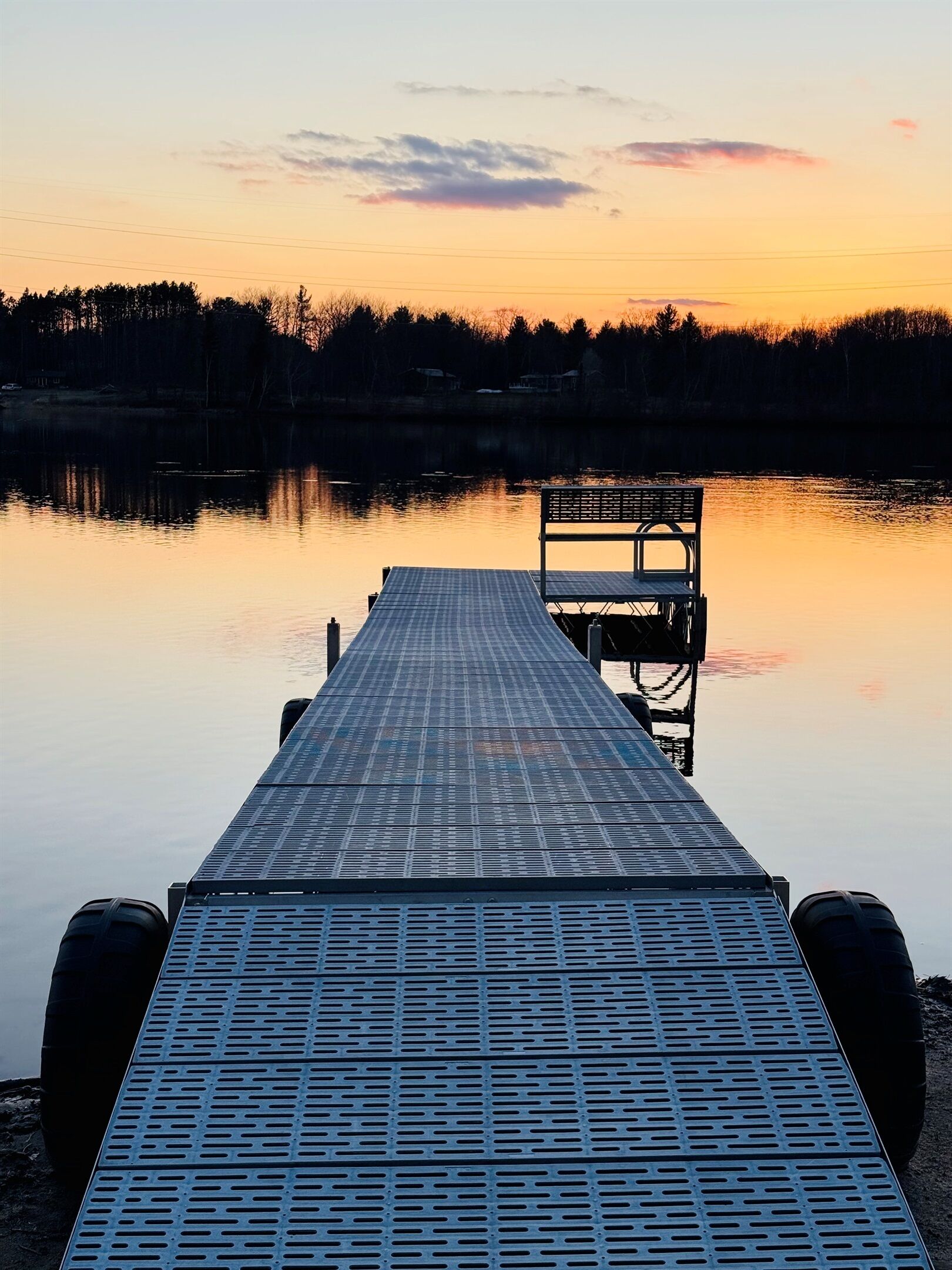 Une jetée s’avançant dans une étendue d’eau calme, avec un banc à son extrémité.