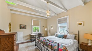 Ein Schlafzimmer mit Bett, Schreibtisch, Kommode und einer Deckenleuchte.