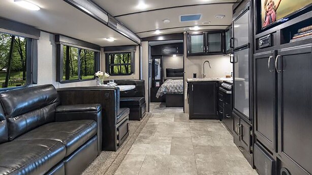En kompakt autocamper indretning med et tekøkken, spiseplads og opholdsområde.