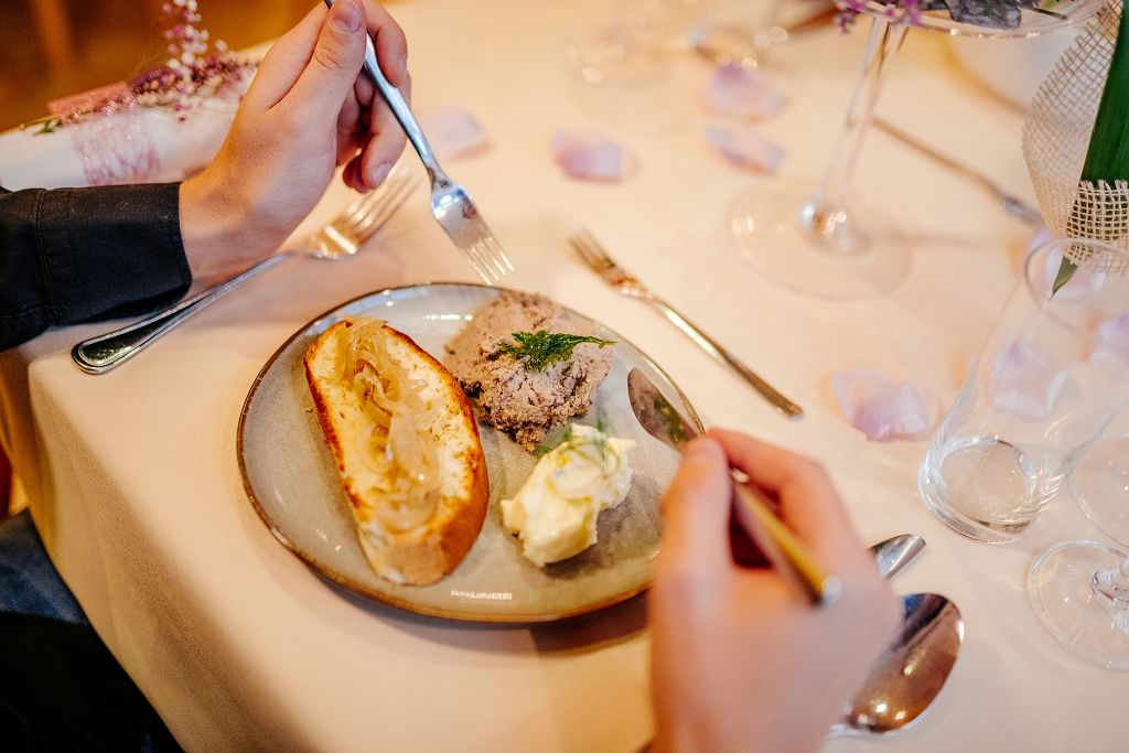 A dining table with a plate of food, a fork, and a spoon.