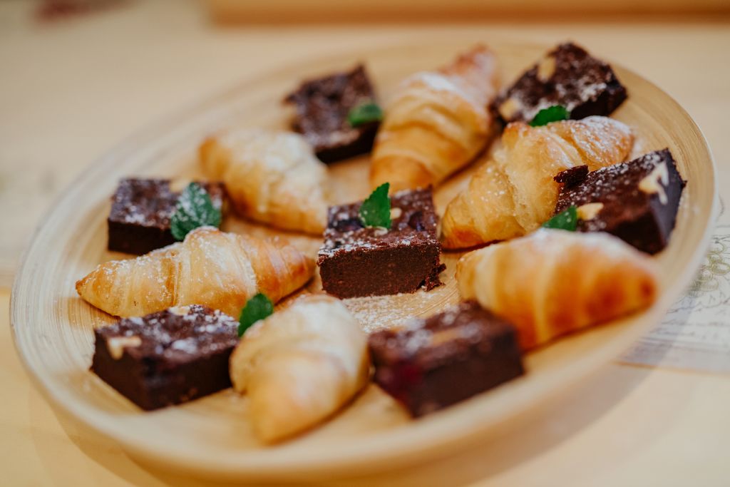 Ein hölzernes Tablett mit verschiedenen Backwaren, darunter Croissants und Schokoladenstückchen.
