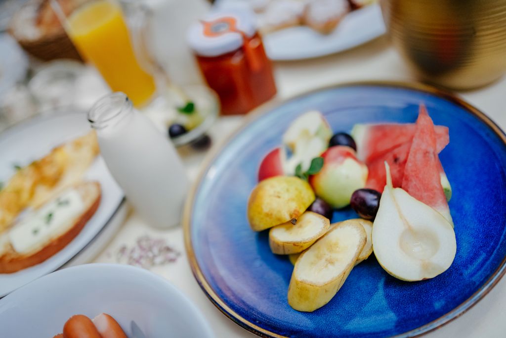 A breakfast setting with a plate of sliced fruits and a glass of orange juice.