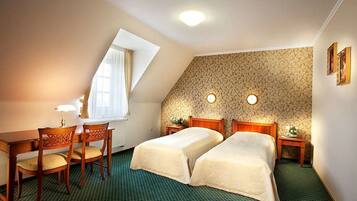 A room with two beds, a desk, chairs, and a window.