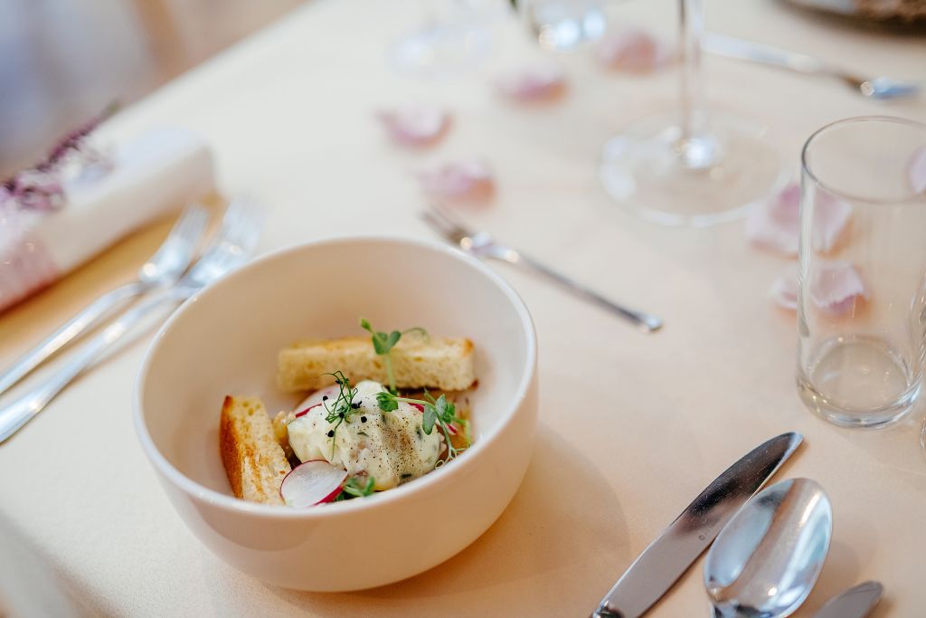 A dining table with a bowl of food, cutlery, and a glass of water.