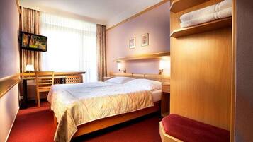 Ein Hotelzimmer mit Bett, Schreibtisch, Fernseher und Kleiderschrank.