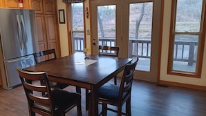 A dining area with a wooden table and chairs, a refrigerator, and large windows with a view of trees. - LOWEST FALL RATES ON WHITE RIVER W/ 2 SLIP COVERED BOAT DOCK! GREAT FISHING!! (Flippin)