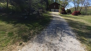 A gravel driveway leading to a red barn with a garage, surrounded by trees and greenery. - LOWEST FALL RATES ON WHITE RIVER W/ 2 SLIP COVERED BOAT DOCK! GREAT FISHING!! (Flippin)