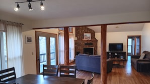 A spacious living area with a stone fireplace, a television, and a cozy seating arrangement. - LOWEST FALL RATES ON WHITE RIVER W/ 2 SLIP COVERED BOAT DOCK! GREAT FISHING!! (Flippin)