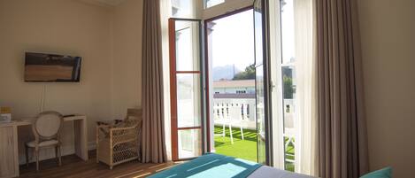 Ein Hotelzimmer mit Bett, Schreibtisch, Stuhl und einem Balkon mit Blick ins Freie.