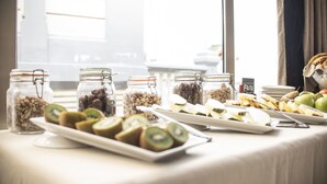 Une table de buffet proposant divers aliments, notamment des fruits et des noix coupés en tranches, disposés sur une table recouverte d’une nappe blanche.