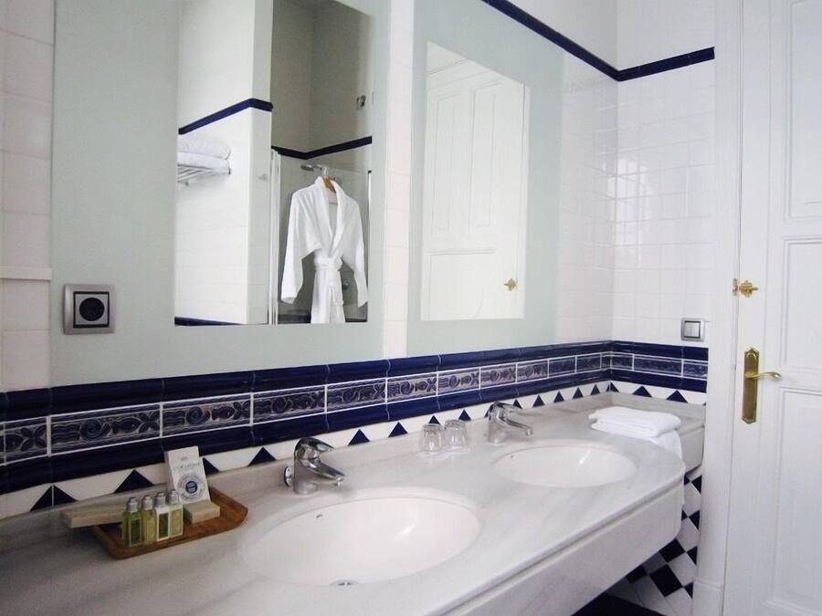 Een badkamer met twee wastafels, een spiegel en een handdoekhouder.