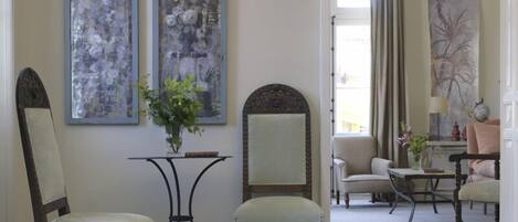A room with two chairs, a small table, and two large abstract paintings on the wall.