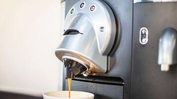 En Nespresso-kaffemaskin som fyller en vit kopp med kaffe.