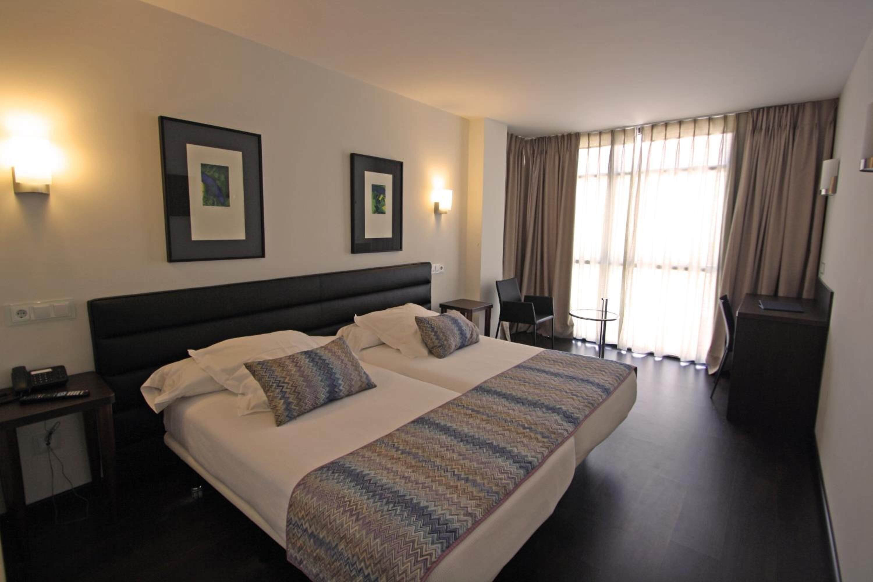 Een hotelkamer met een groot bed, twee nachtkastjes, een bureau en een stoel.