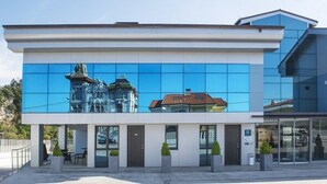 Un edificio moderno con una amplia fachada de vidrio reflectante, techo plano y diseño simétrico.