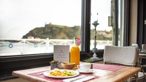 Una mesa de desayuno con un plato de comida, un vaso de zumo de naranja, una taza y un menú.