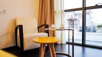 Una habitación moderna con una silla blanca, un taburete de madera y una mesa con taza y plato.
