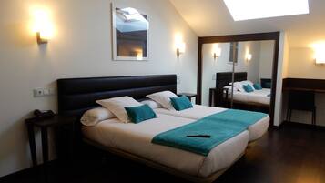 A double bed with a dark headboard, two bedside tables, a desk, and a large mirror.