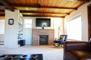 Cozy living room with a brick fireplace, flat-screen TV, and comfortable seating areas.