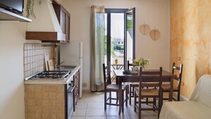 Een kleine keuken met een kookplaat, oven en een eethoek met tafel en stoelen.