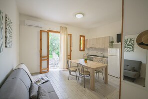 Un espace de vie compact comprenant un coin cuisine, un coin repas et un canapé.