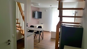 A modern living room with a staircase, a dining area, and a TV mounted on the wall. - Neckarzeit (Neckarwestheim)