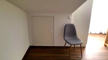 Una habitación con piso de madera, una puerta blanca y una silla gris.