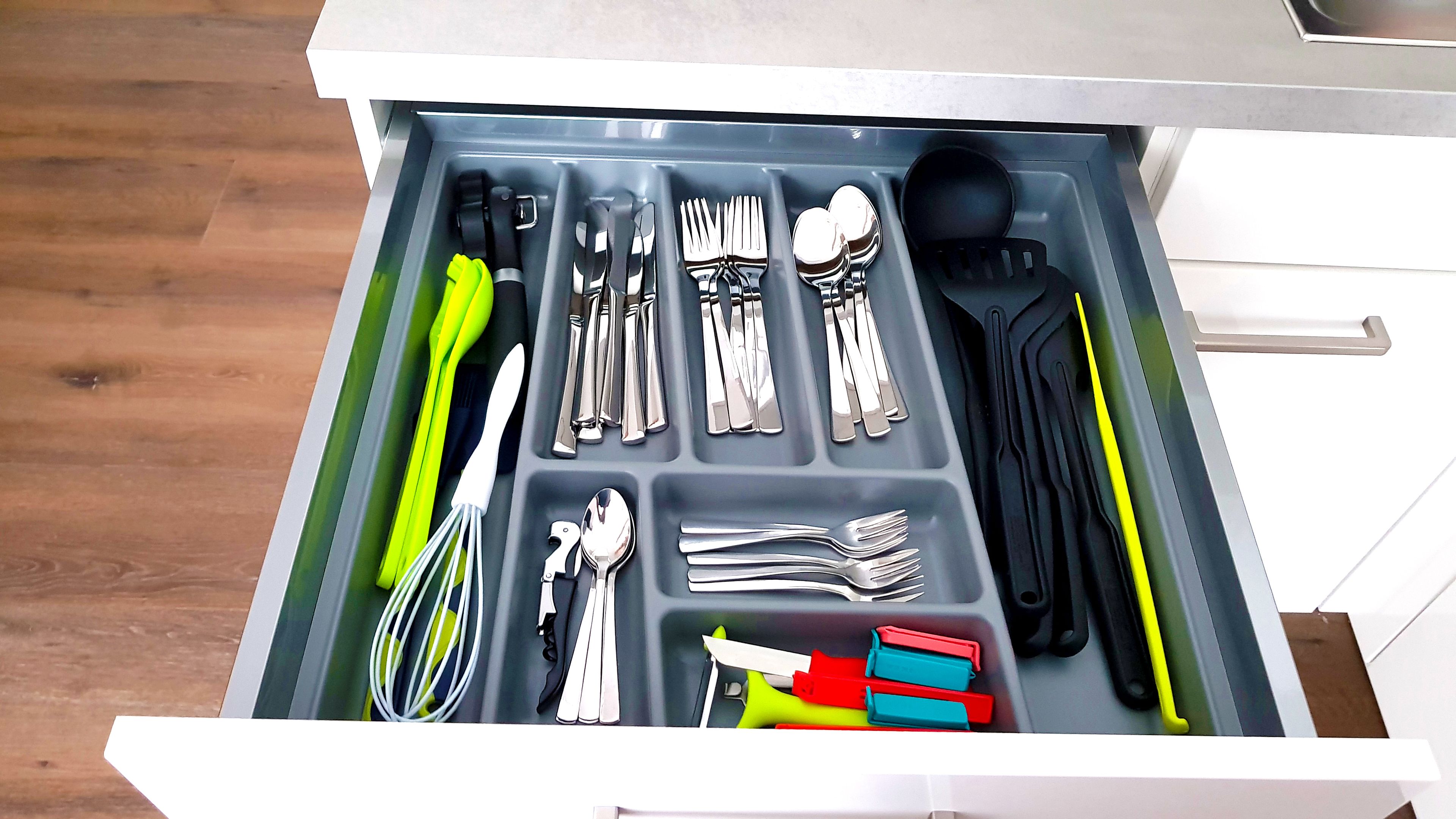 A drawer with compartments containing various kitchen utensils and tools.