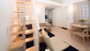 Un appartement moderne avec une chambre en mezzanine, un coin repas et une cuisine.