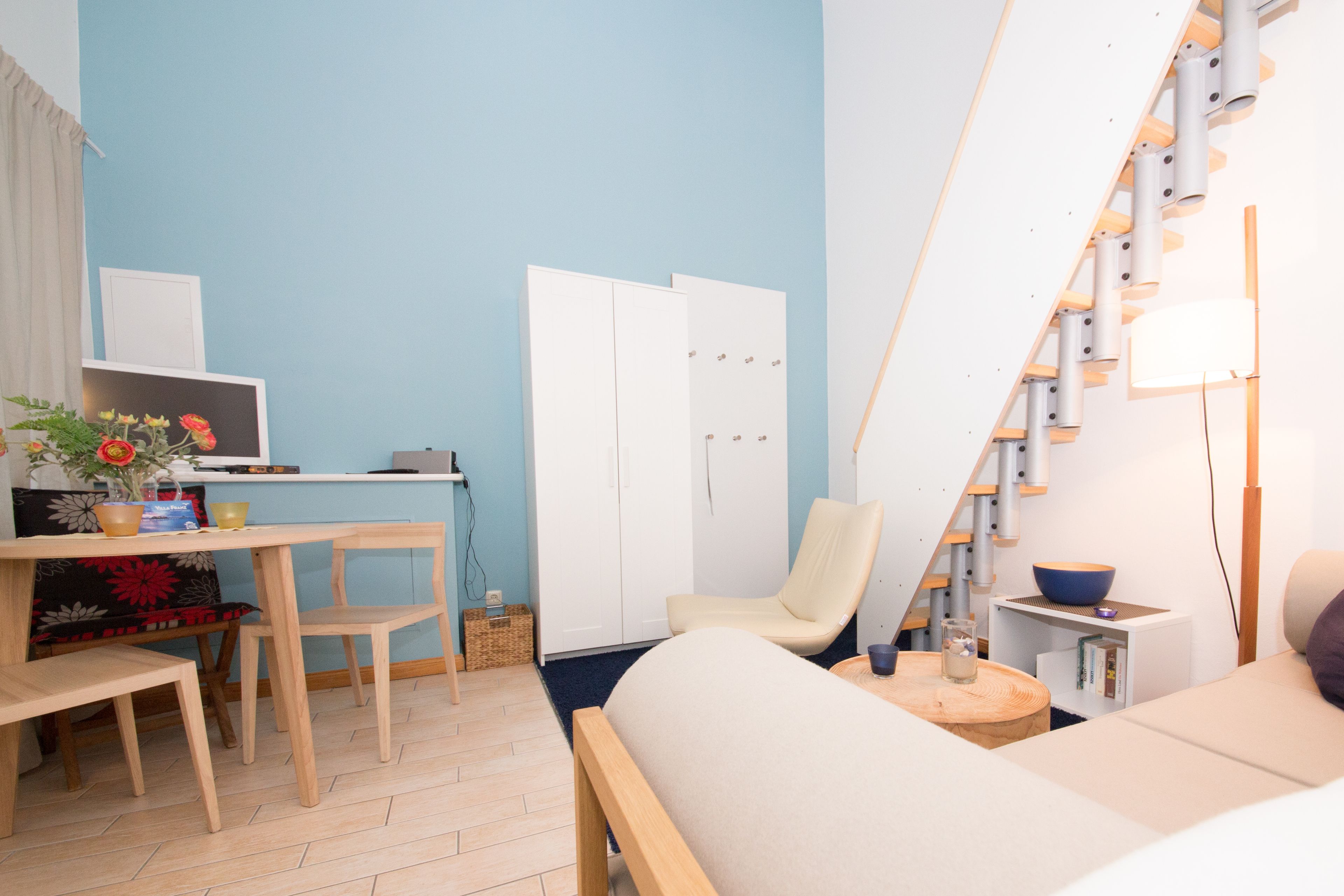 Une pièce moderne comprenant un bureau en bois, une chaise, un canapé et un escalier doté d’une rampe.