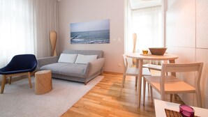 Un salon moderne avec un canapé gris, un fauteuil bleu, une table basse en bois et une table à manger avec des chaises.