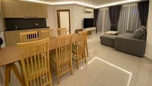 A modern living room with a dining area, a sofa, and a flat-screen TV. - Maldives Resort by PSR ASIA (Pattaya)
