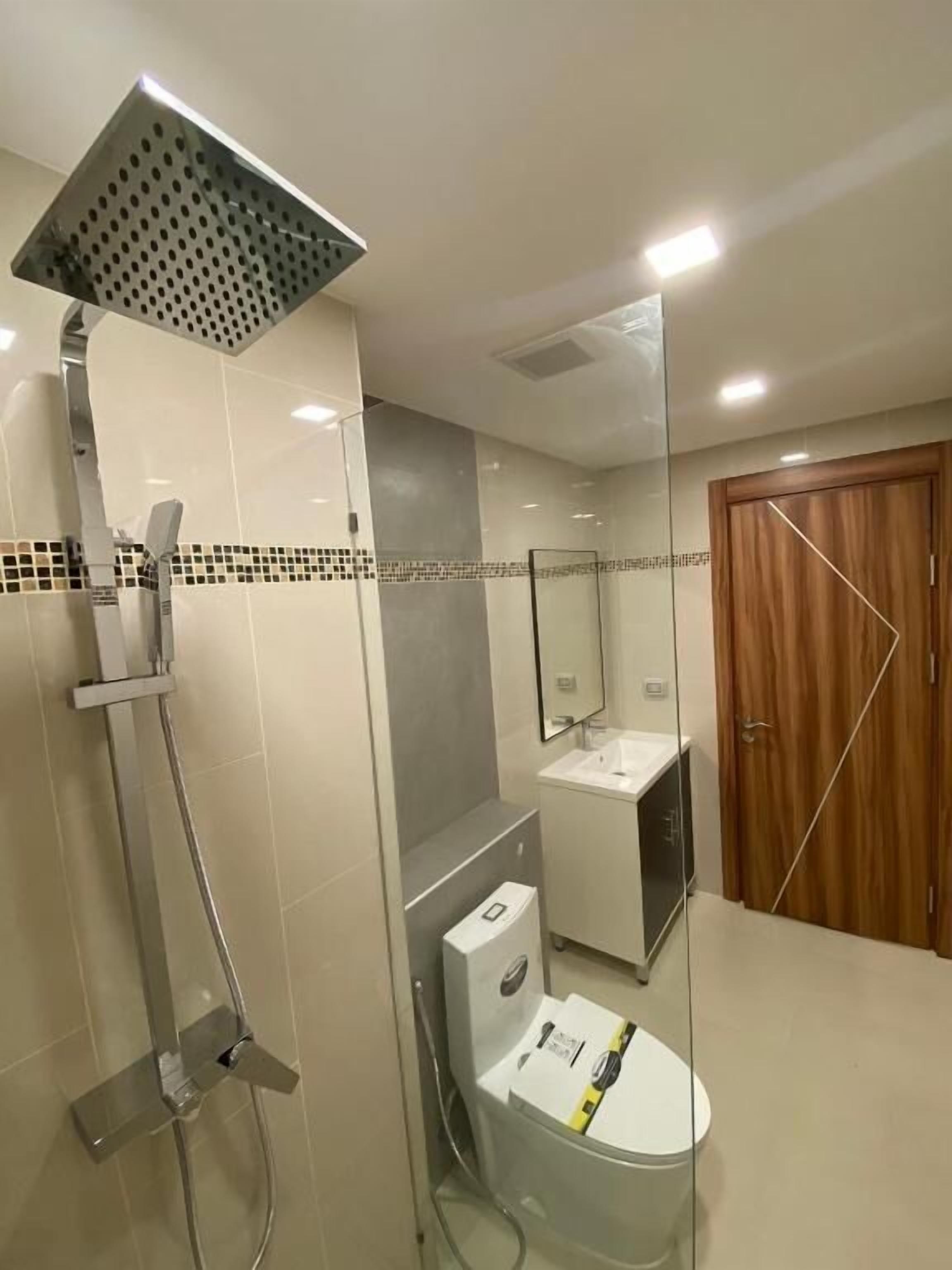 A modern bathroom with a glass-enclosed shower, a toilet, and a vanity with a mirror.