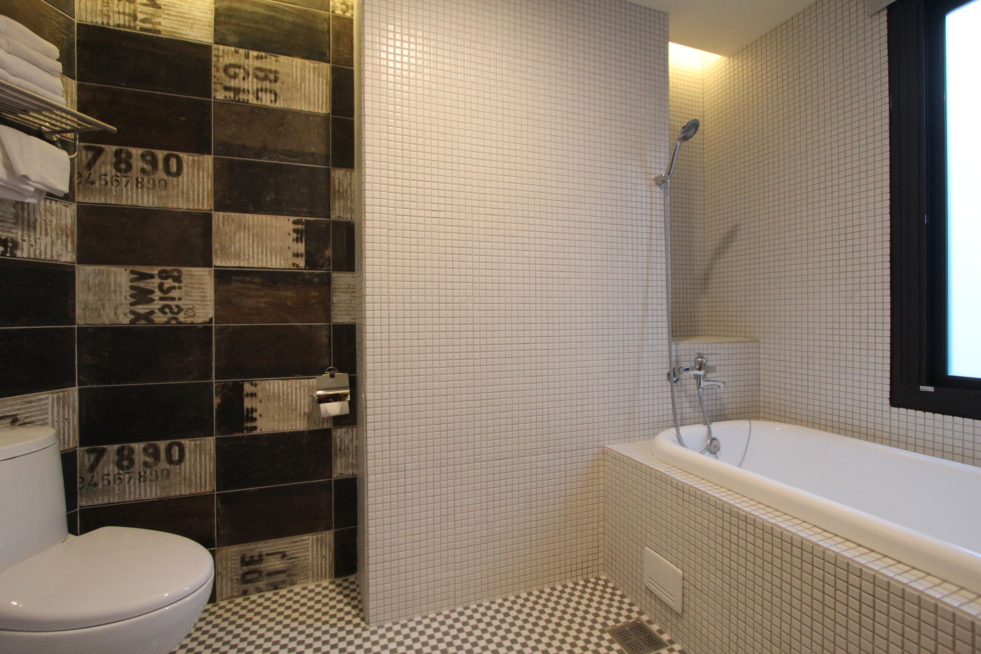 Une salle de bain avec un carrelage à motifs géométriques, des toilettes, une baignoire et des murs recouverts de carreaux ornés de chiffres.