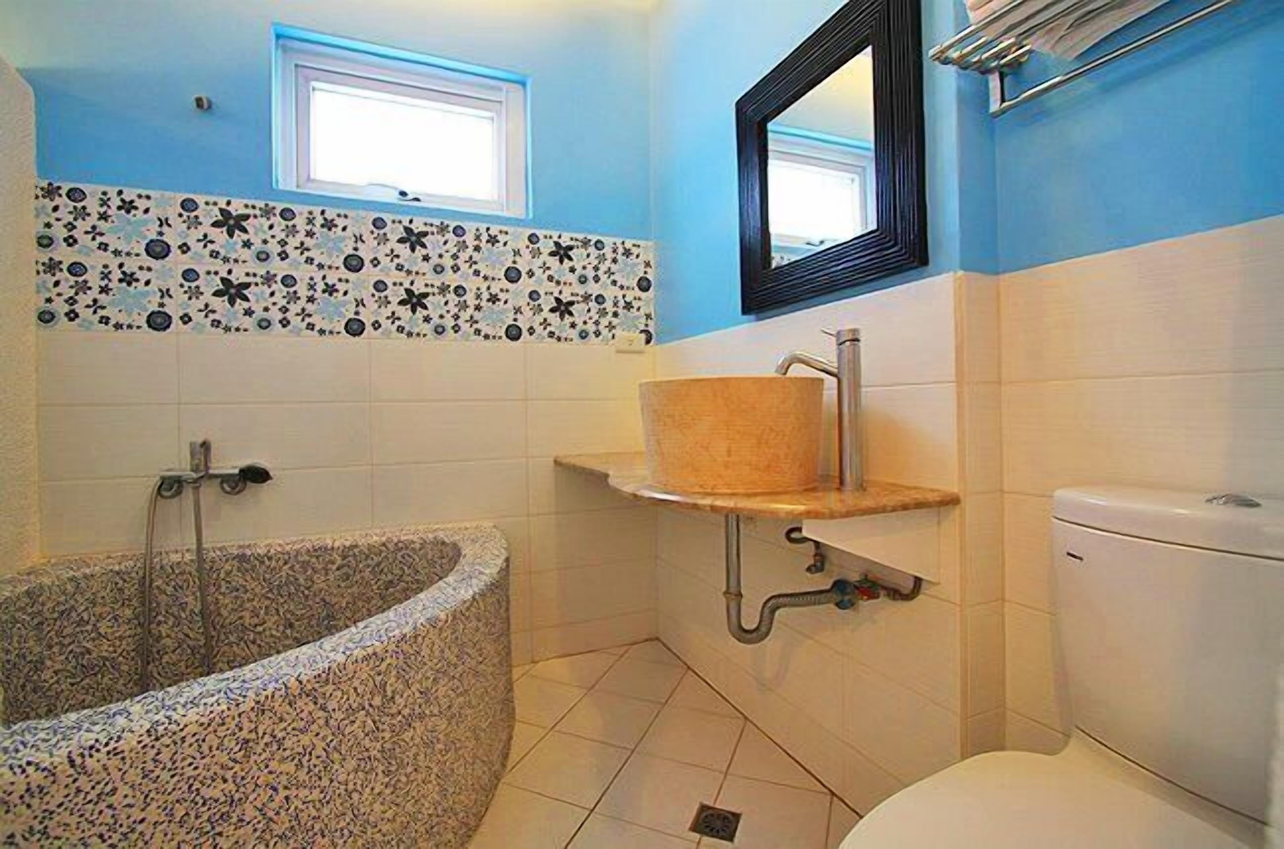 A bathroom with a freestanding bathtub, a sink with a wooden countertop, and a toilet.