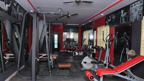 Un gimnasio con equipos de ejercicio variados, incluyendo cintas de correr, máquinas de pesas y una banca.