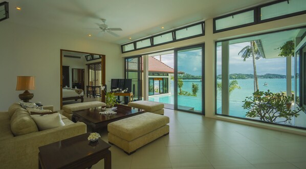 Amplio salón con un ventanal que da a una piscina y al mar.
