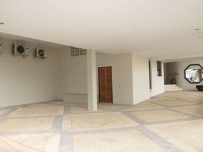 Un interior amplio con suelo de baldosas, una puerta de madera y unidades de aire acondicionado en la pared.
