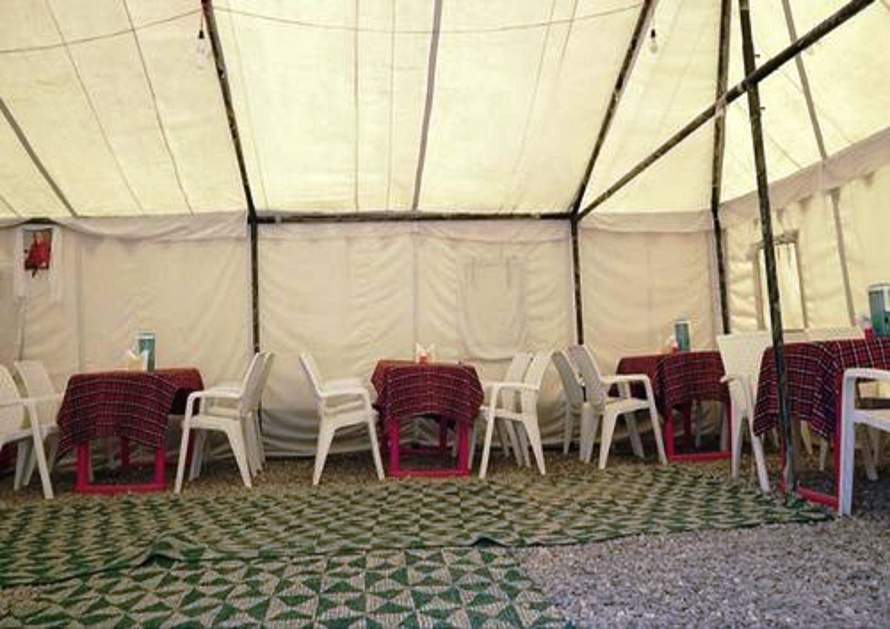 A tent with tables and chairs arranged inside.