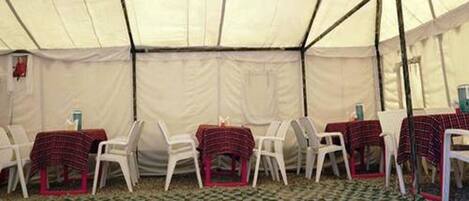 A tent with tables and chairs arranged inside.