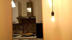 A kitchen with white cabinets, a wooden countertop, and a hanging light fixture with exposed bulbs. - Il Mare di Roma Luxury (Rome)