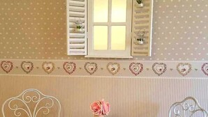 A room with a small round table and two chairs, a window with shutters, and a patterned wall. - Il Mare di Roma Luxury (Rome)