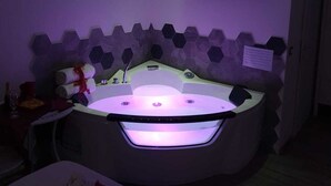 A modern bathroom with a freestanding bathtub, a flat-screen TV mounted on the wall, and a hexagonal tile backsplash. - Il Mare di Roma Luxury (Rome)
