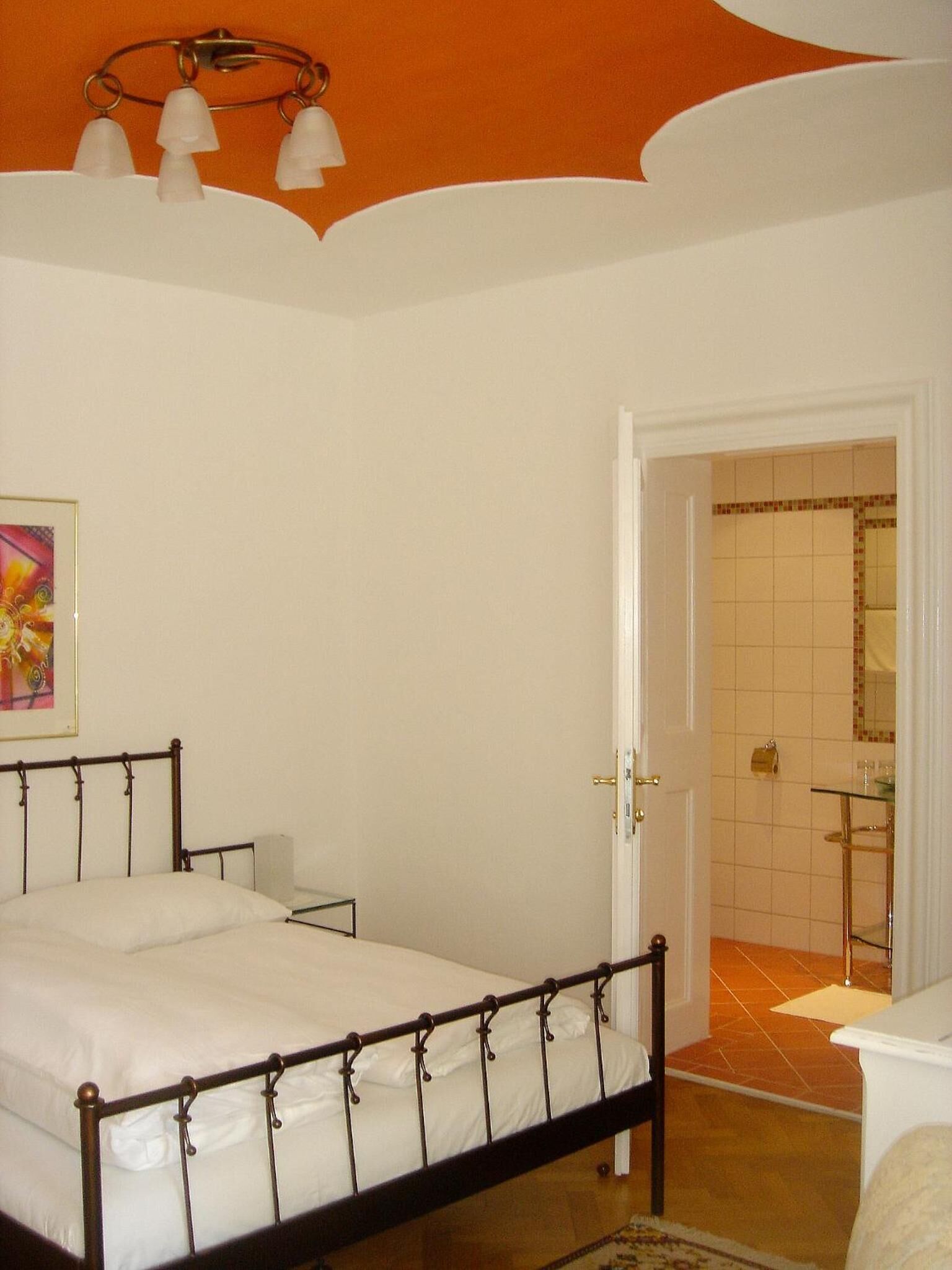 Une chambre à coucher comprenant un lit, une table de chevet et une porte donnant sur une salle de bain.