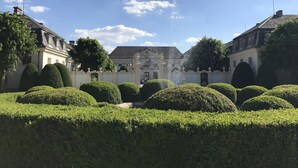 Un patio con una fuente, setos cuidados y arquitectura clásica.