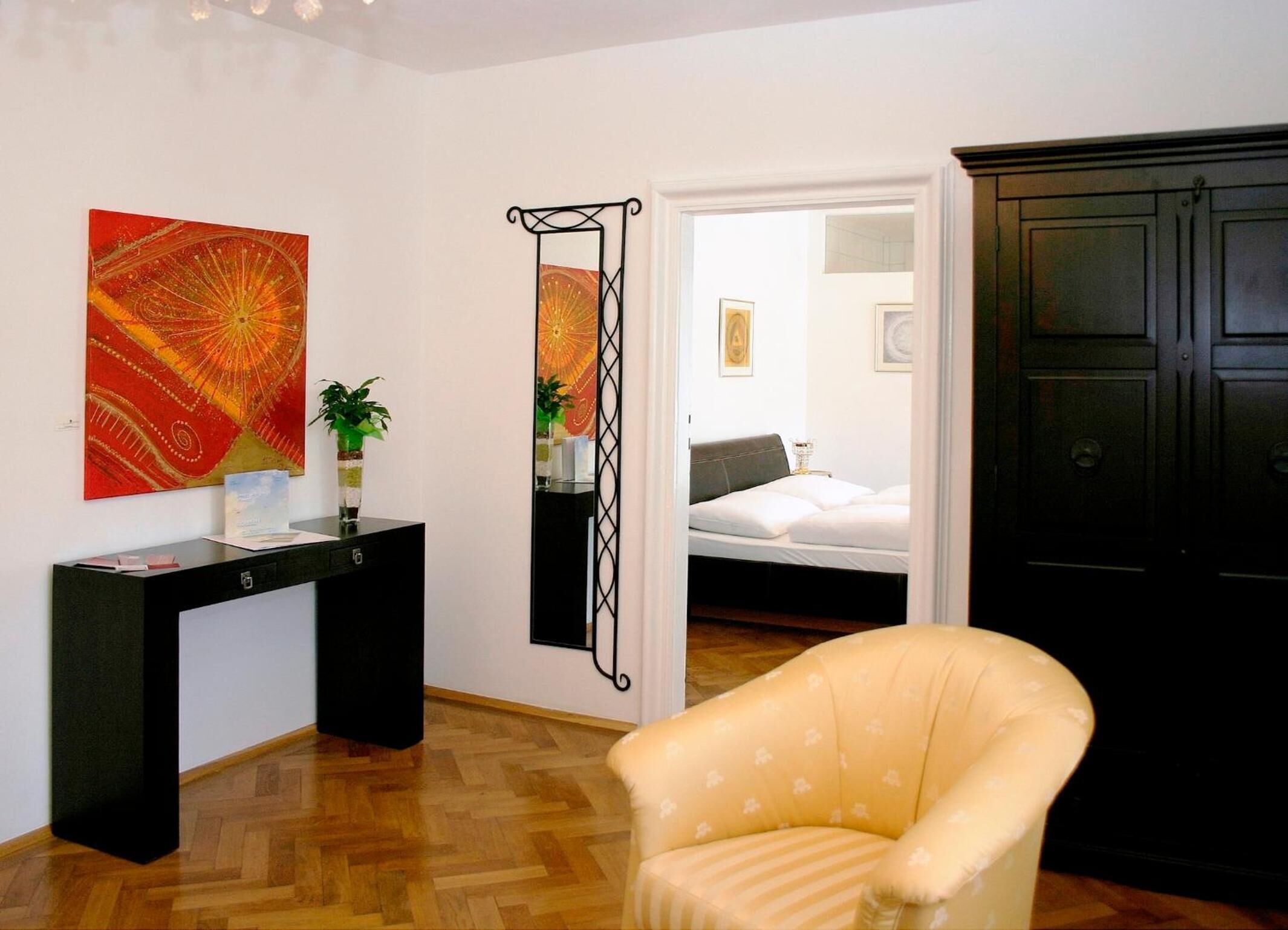 Quarto com cama, escrivaninha, cadeira e obras de arte nas paredes.