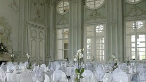 Un salón de banquetes con frescos ornamentales en el techo, amplias ventanas y mesas dispuestas para un evento formal.