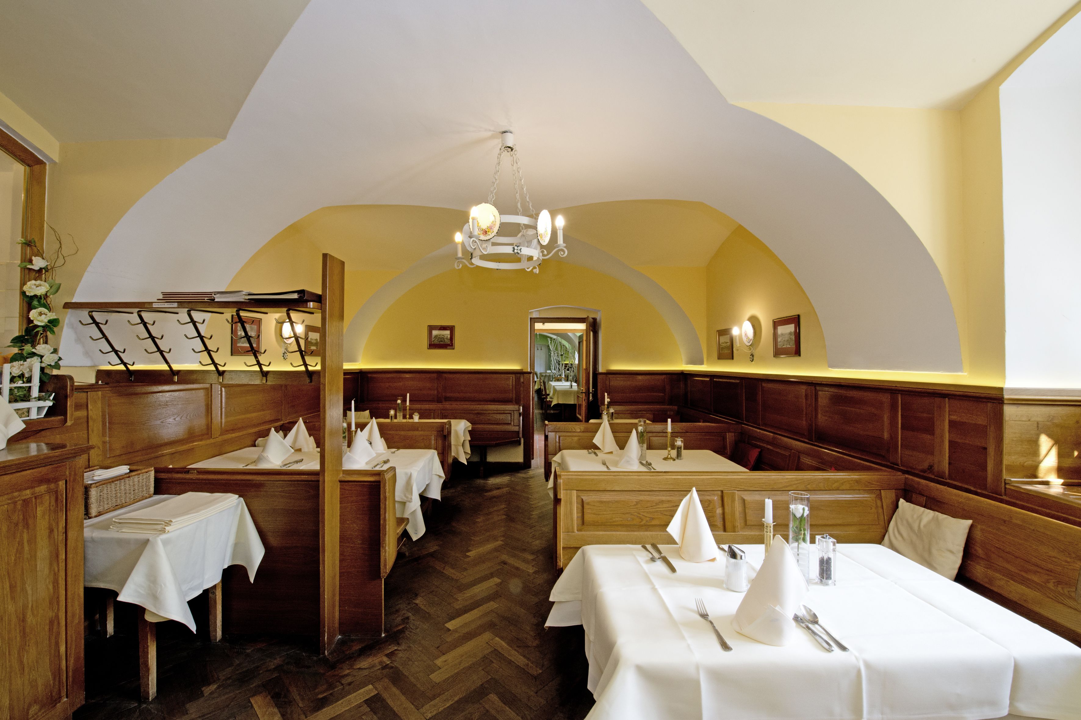 Un restaurante con cabinas de madera, manteles blancos y un candelabro.