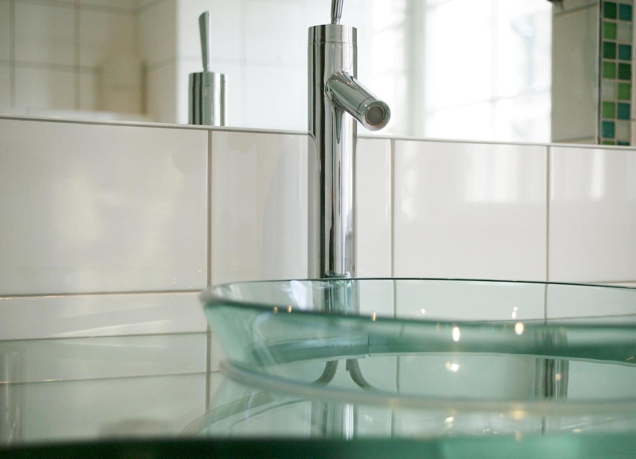 A modern bathroom with a glass sink and chrome faucet.