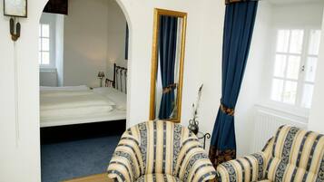 Una habitación con cama, sofá, espejo y ventana con cortinas.